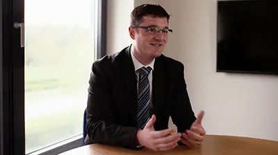 A man in a suit responding to interview questions