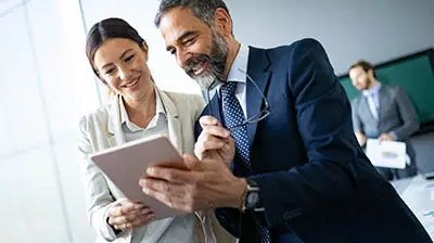 To colleagues sharing a smart tablet while smiling 